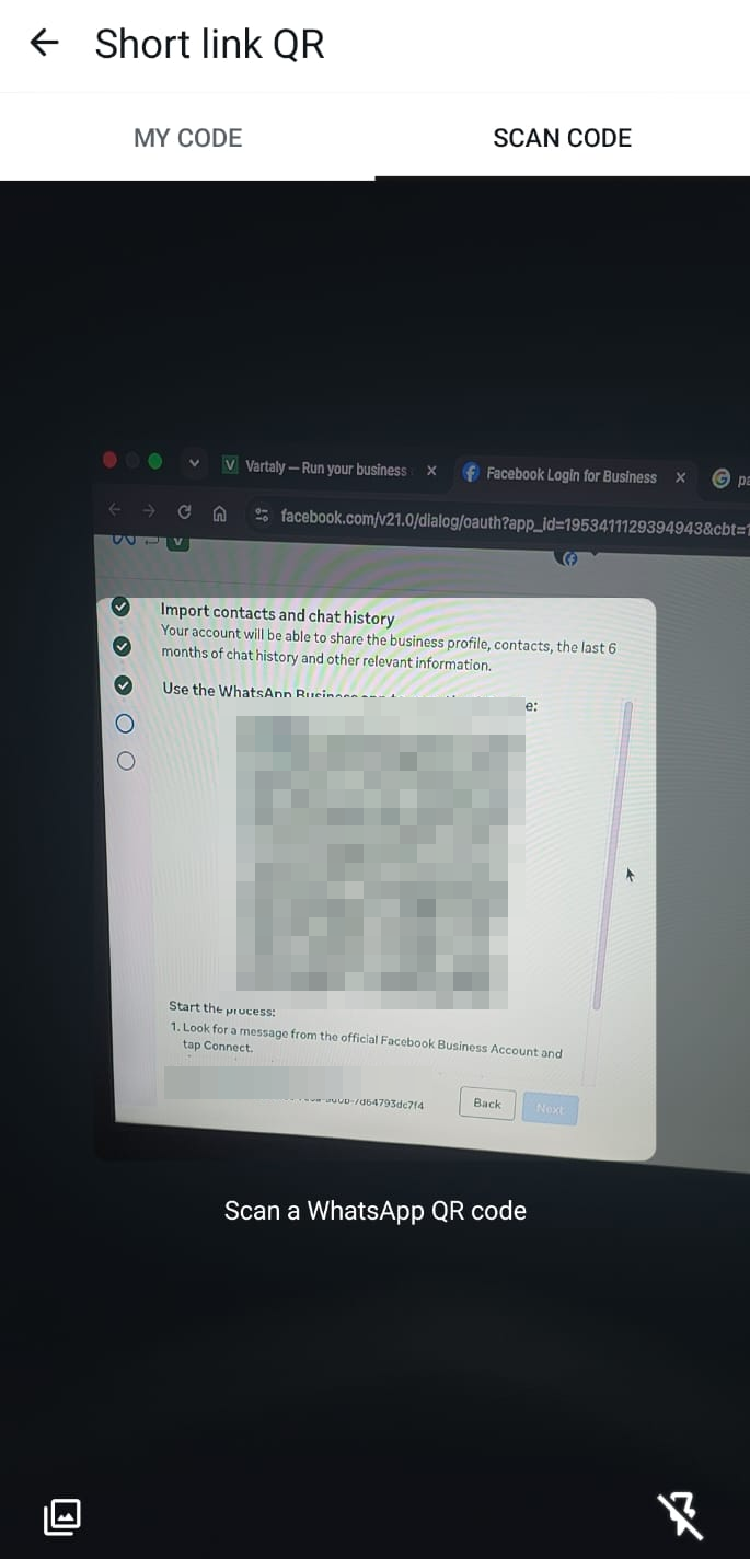 Phone scanning the QR code shown on the laptop using the WhatsApp Business app